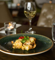 Elegant dining setup at Louis Fitzgerald Hotel with delicious appetiser, wine, and candlelit ambience.