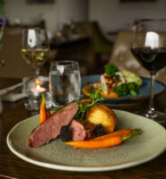 Elegant dining table with gourmet dish, wine, and soft lighting at Louis Fitzgerald Hotel.
