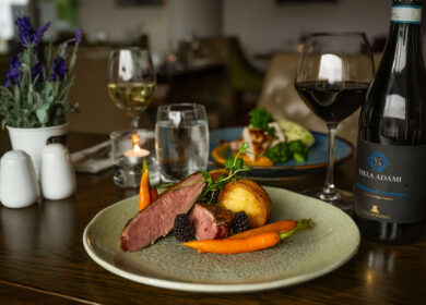 Elegant dining table with gourmet dish, wine, and soft lighting at Louis Fitzgerald Hotel.