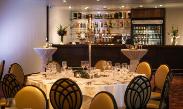 Elegant dining setup in a luxurious hotel venue with a well-stocked bar and candlelit tables.