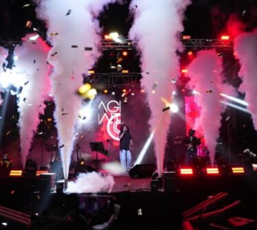 A vibrant concert stage with smoke effects and colourful lights.