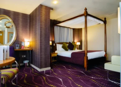 Elegant hotel room with a four-poster bed and cosy seating area.