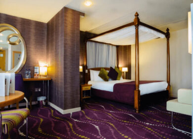 Elegant hotel room with a four-poster bed, modern decor, and warm lighting at Louis Fitzgerald Hotel.
