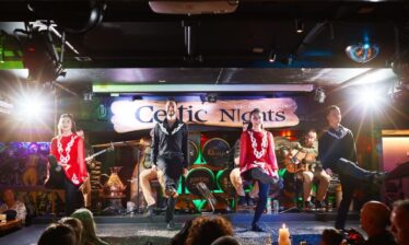 Irish dancers performing lively steps on stage at Louis Fitzgerald Hotel's Celtic Nights.