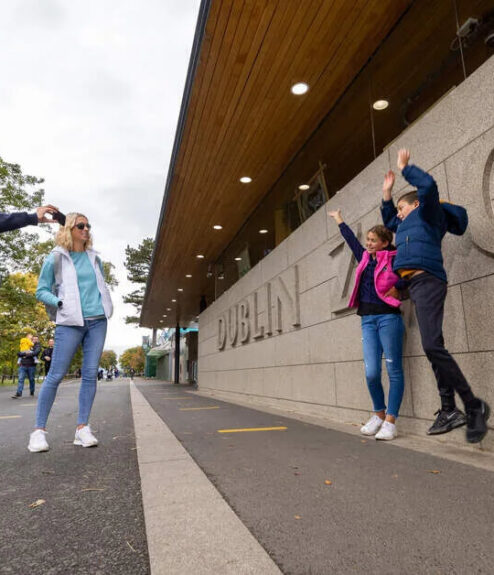 People enjoying a day out at Dublin Zoo, with friends taking photos near a modern entrance.
