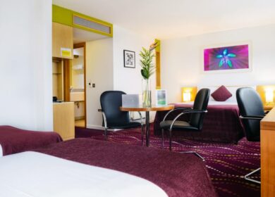 Spacious hotel room with twin beds, modern decor, and a seating area at Louis Fitzgerald Hotel, Dublin.
