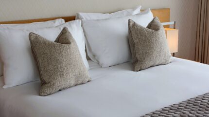 Luxurious king bed with soft pillows in a cosy hotel room at Louis Fitzgerald Hotel, Dublin.