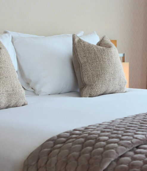 Luxurious double bed with plush pillows and elegant bedding in a cosy hotel room.
