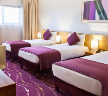 Spacious triple room with purple decor and soft lighting at Louis Fitzgerald Hotel, Dublin.