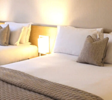 Spacious and inviting double beds in a cosy, well-lit hotel room.