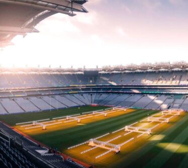 Empty stadium with green grass and sunlight streaming in.