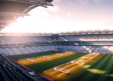 Empty stadium with green grass and sunlight streaming in.