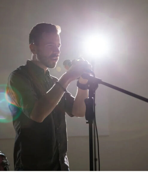 Man preparing to sing with microphone in well-lit room at Louis Fitzgerald Hotel.