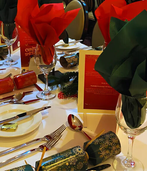 Festively decorated dinner table at Louis Fitzgerald Hotel with red and green napkins.