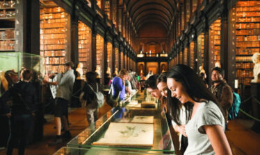 Visitors explore the historic library, admiring displays and shelves of antique books.