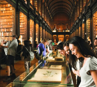 Visitors explore the historic library, admiring displays and shelves of antique books.