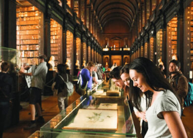 Visitors explore the historic library, admiring displays and shelves of antique books.