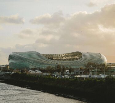 Aviva Stadium at sunset, visible from a serene riverside view in Dublin City.