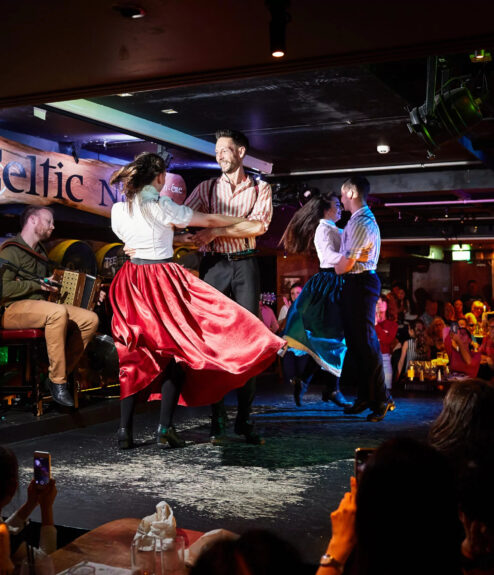 Traditional Irish dancers perform with live musicians at a lively Dublin venue.
