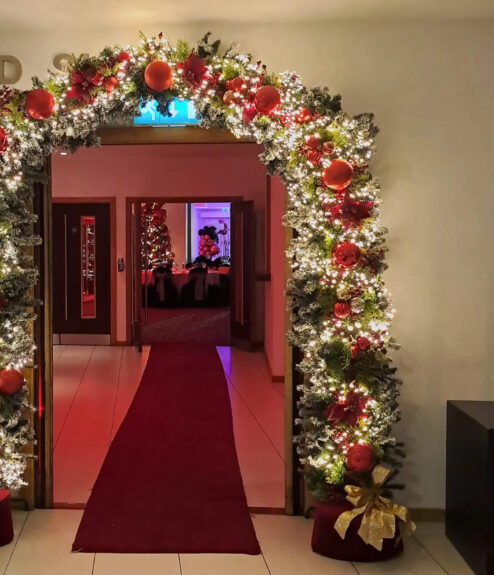 Festive archway with lights and decorations at Louis Fitzgerald Hotel entrance.