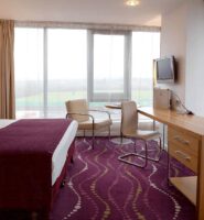 Elegant hotel room with a large bed, desk, and seating area by the window.