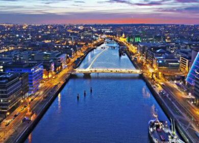 Vibrant Dublin sunset over River Liffey, city lights reflecting, calm waters, and bustling streets.