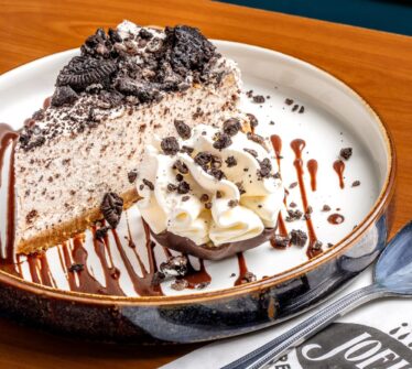 Oreo cheesecake with whipped cream served elegantly on a plate.