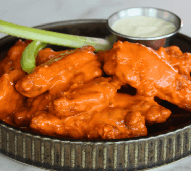 Spicy chicken wings with dip and celery stick on a plate at the Louis Fitzgerald Hotel.