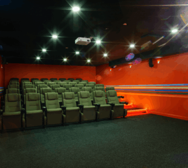 Cosy hotel cinema room with rows of plush seating in a warmly lit setting.