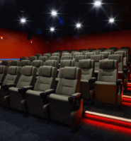 Modern hotel cinema room with plush seating and vibrant red walls at Louis Fitzgerald Hotel.