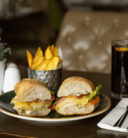Gourmet sandwich with chips and drink on elegant hotel table setting.