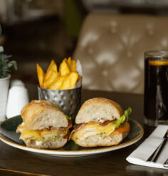 Gourmet sandwich with chips and drink on elegant hotel table setting.