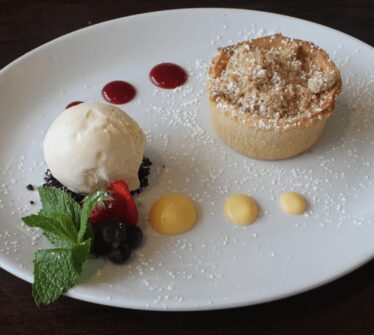 Dessert plate with ice cream, pie, berries, and mint.