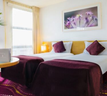 Cosy twin room at Louis Fitzgerald Hotel with plush purple accents and elegant décor.
