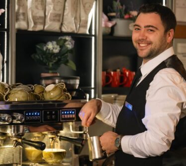 Friendly barista making coffee at Louis Fitzgerald Hotel café.