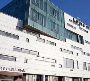 Modern exterior of Louis Fitzgerald Hotel, Dublin, under a clear blue sky. Visible text: "LJ's Bar & Restaurant.