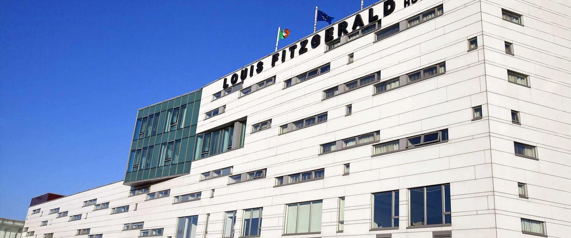 Modern facade of Louis Fitzgerald Hotel in Dublin with blue sky backdrop.