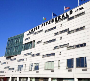Modern facade of Louis Fitzgerald Hotel in Dublin with blue sky backdrop.