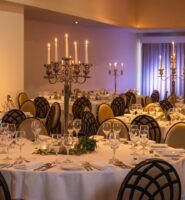 Elegant dining setup with white tablecloths and candlelit chandeliers at Louis Fitzgerald Hotel.