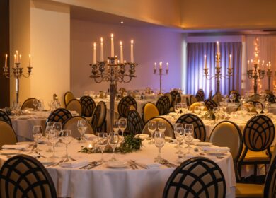 Elegant dining setup with white tablecloths and candlelit chandeliers at Louis Fitzgerald Hotel.