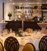 Elegant dining setup at Louis Fitzgerald Hotel with candlelit centrepiece and stocked bar.
