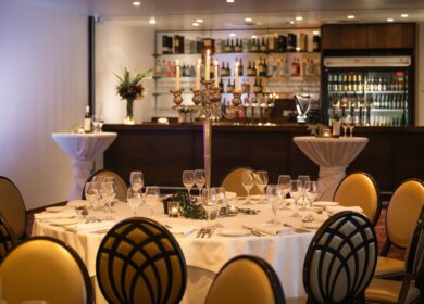 Elegant dining setup at Louis Fitzgerald Hotel with candlelit centrepiece and stocked bar.