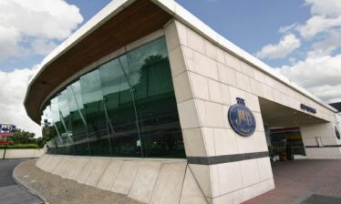 Modern glass facade of Louis Fitzgerald Hotel in Dublin with clear skies above.