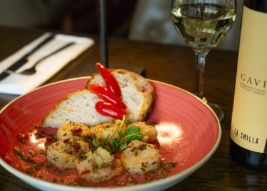 Elegant dining with shrimp, bread, roasted peppers, wine glass, and bottle at Louis Fitzgerald Hotel.