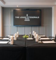 Elegant meeting room at Louis Fitzgerald Hotel with chairs, bottles, and notepads set out.