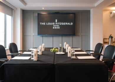 Elegant meeting room at Louis Fitzgerald Hotel with chairs, bottles, and notepads set out.