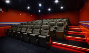 Cosy hotel cinema room with plush seats and vibrant red walls, creating an inviting atmosphere.