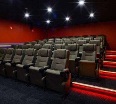 Cosy hotel cinema room with plush seats and vibrant red walls, creating an inviting atmosphere.