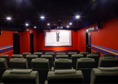 Comfortable theatre room at Louis Fitzgerald Hotel with plush seats and dim lighting.