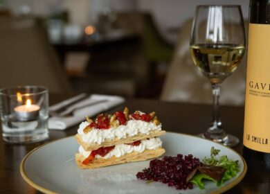 Elegant dessert and white wine on a table at Louis Fitzgerald Hotel, with warm ambient lighting.